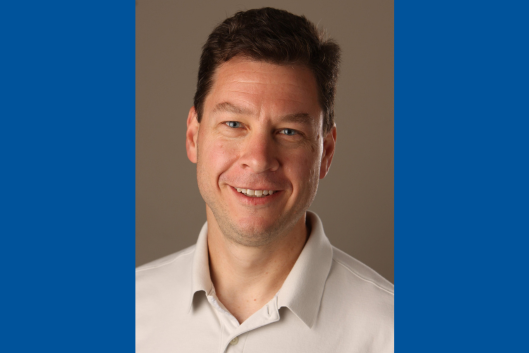 Pictured is Dr. Scott Schmidler a man with short dark brown hair light skin and blue eyes smiling. He is wearing a light-colored collared shirt